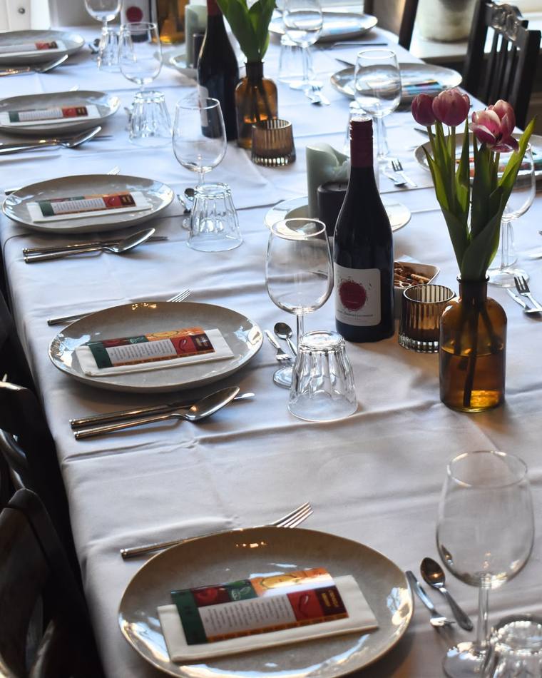 A candlelit table set with wine, tulips, and menu cards