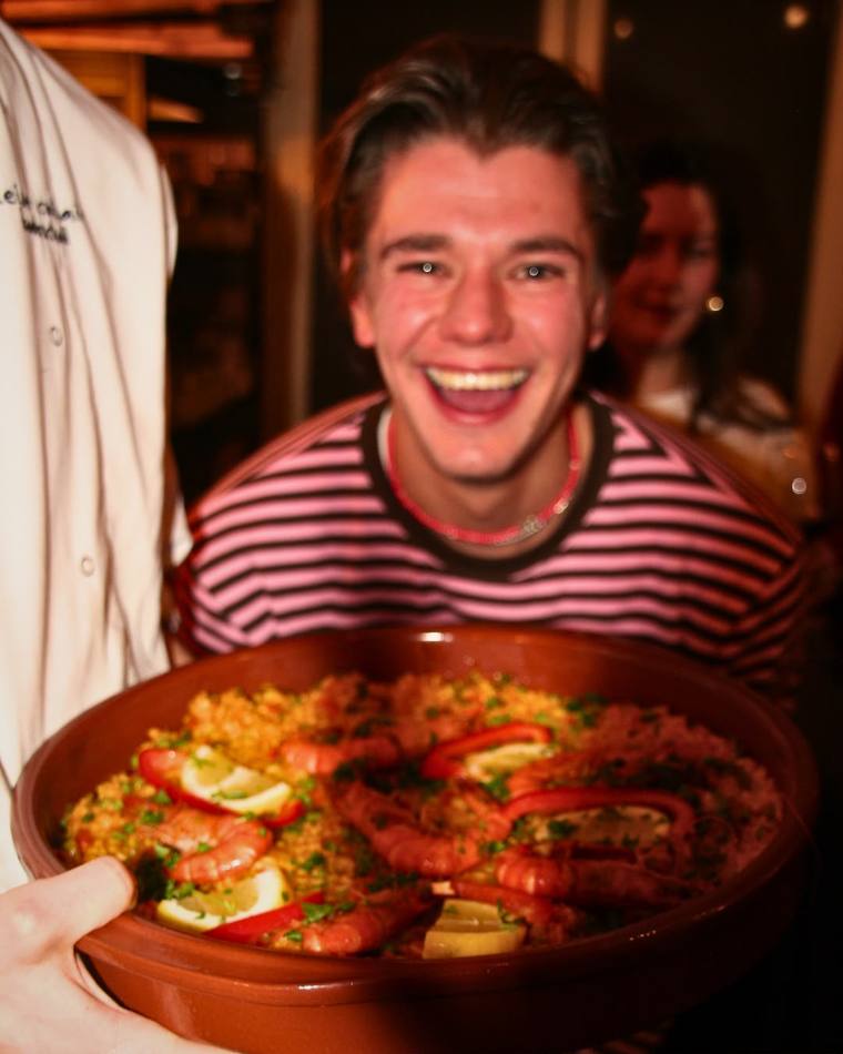 A guest laughing while holding a full pan of Fork It paella