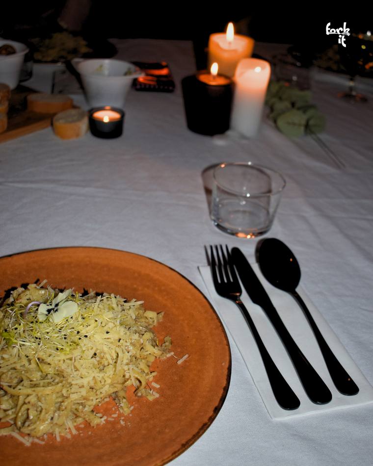A herb and cheese pasta dish plated by candlelight