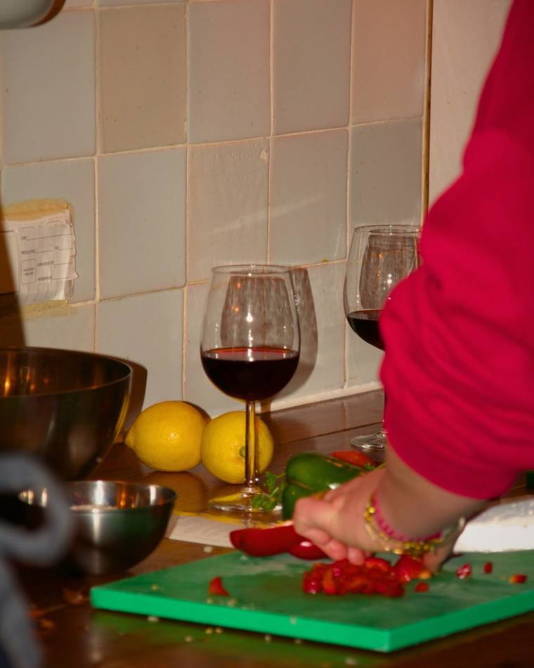 Chopping fresh peppers and tomato beside a glass of red wine