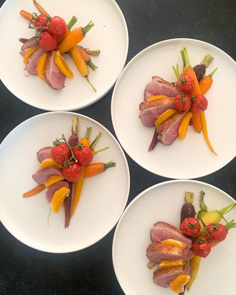 Four plates of roasted duck breast ready to be served