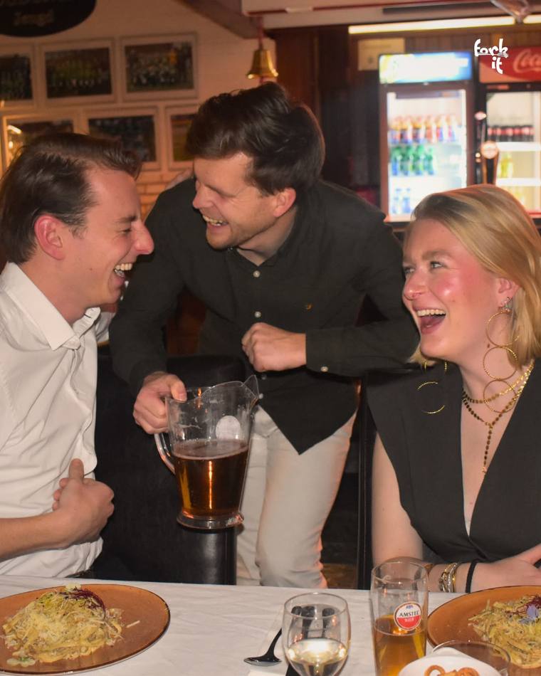 Friends laughing together over dinner and a jug of beer