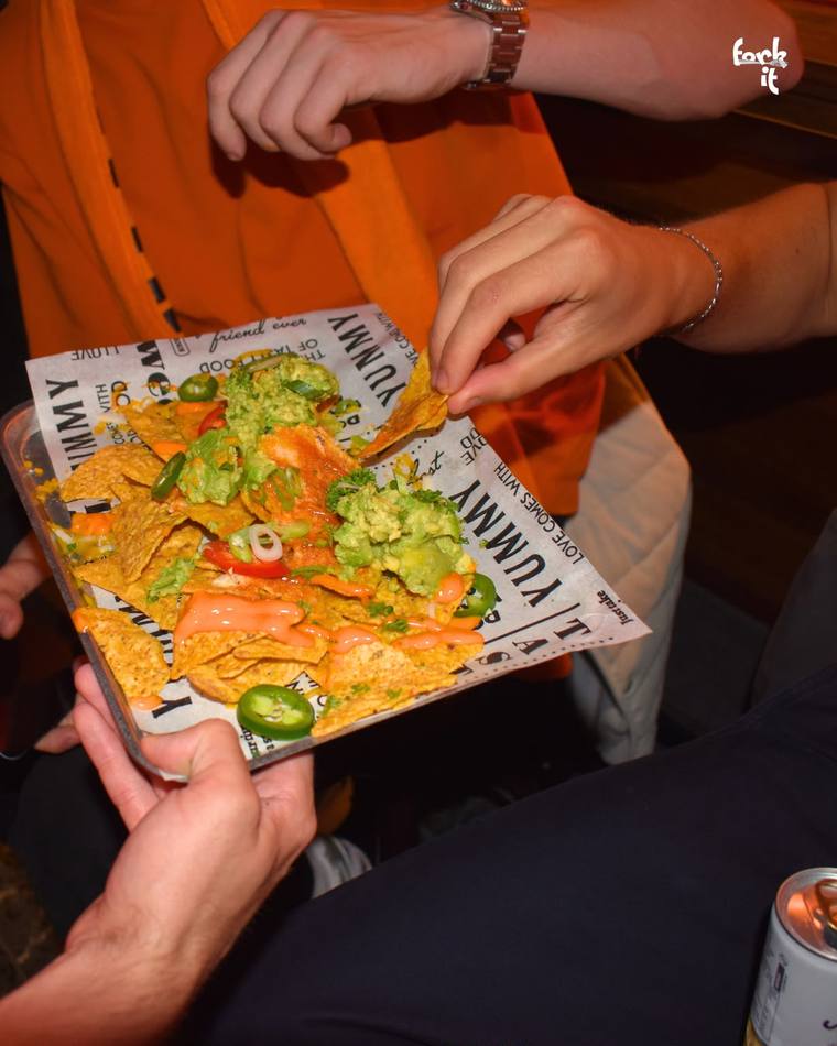 Loaded nachos with guacamole and jalapeño being shared